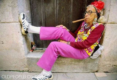 Funky, older woman, dressed colorfully and smoking a cigar